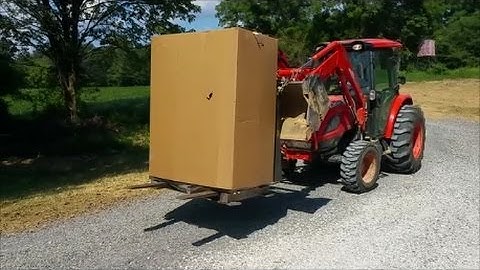 Kioti NX6010 Unloading 650 lb safe with jerry-rigged pallet forks chained to bucket