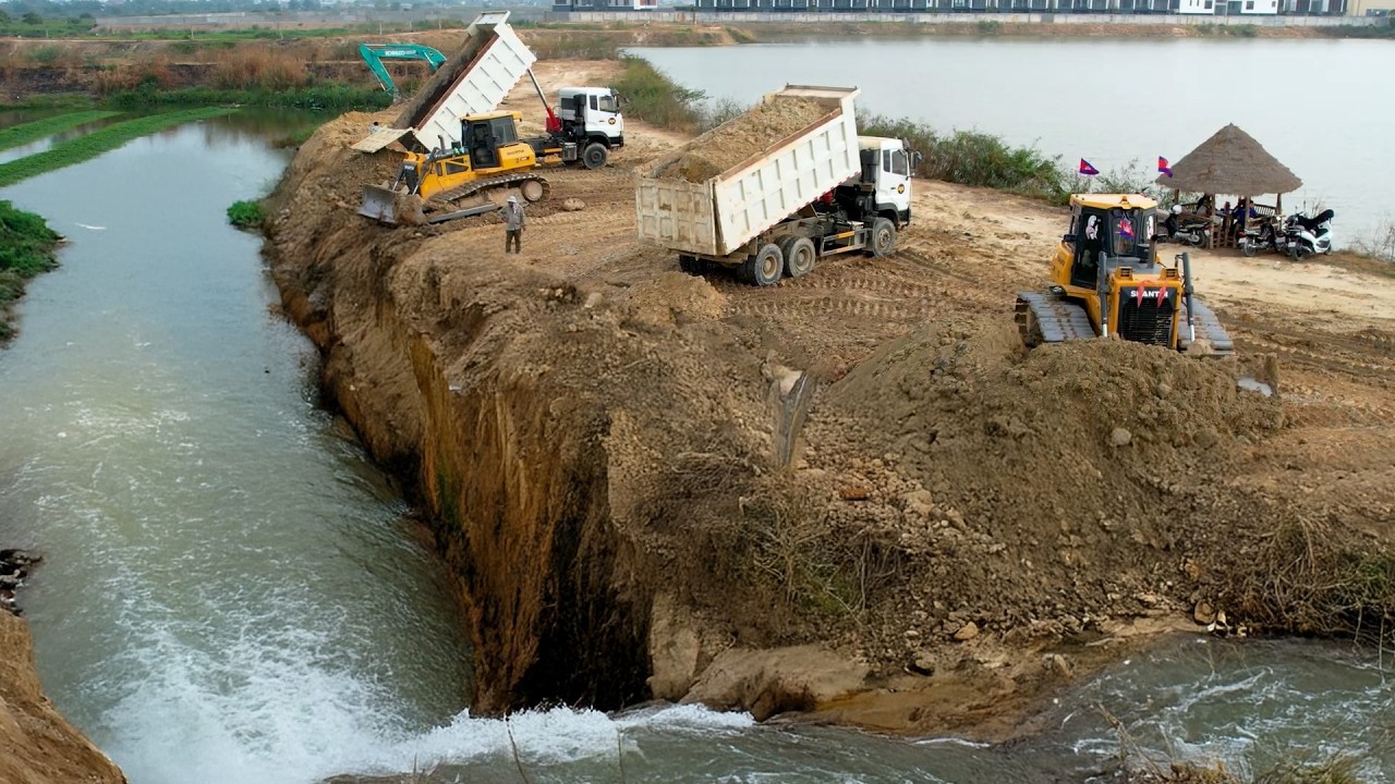 Project Showing Action by Bulldozer Pushing & Dump Truck Dumping dirt to Delete pond
