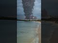Large fire tornado is coming out of the sky over a beach