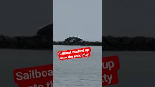 Sailboat washed up onto the rock jetty in Huntington Beach