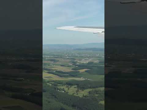 夏の北海道 旭川空港上空から遠くにビルが林立する旭川市街が見えるAIRDO-B767機内窓からの景色