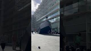 Skateboarder rides down black oversized rock statue at MACBA and lands on wrists