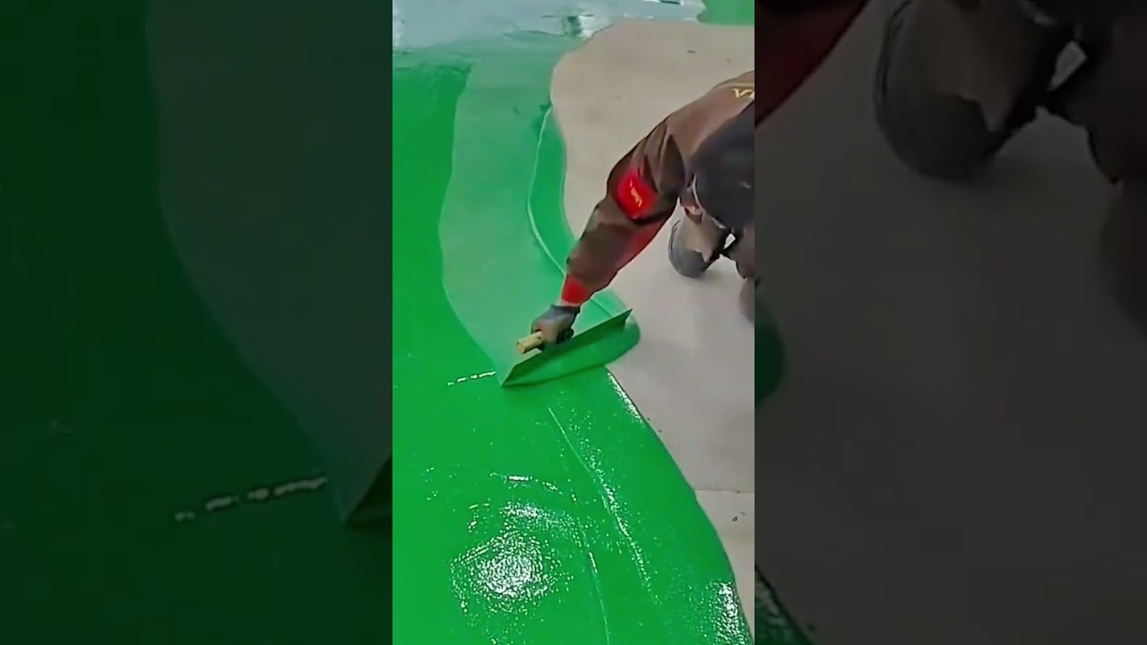 applying green epoxy resin on the floor surface with a squeegee tool for a smooth and glossy finish