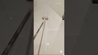 Applying a smooth white epoxy coating to the floor surface using a specialized roller for a neat