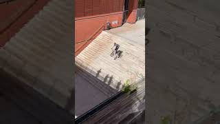 BMX riders jumps stairs then falls off bike when landing and bumps head on the ground