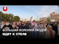 Большая колонна протестующих идет к стеле по проезжей части вечером 23 сентября