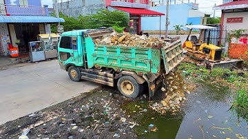 nicely start up new project landfill flooded area ! Bulldozer push stone with truck unloading stone