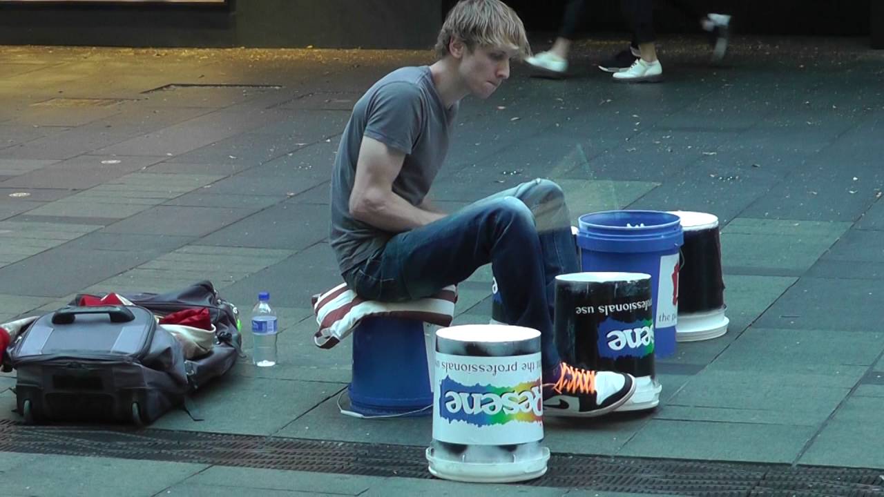 Young man plays paint buckets as drums in Sydney's CBD, Australia