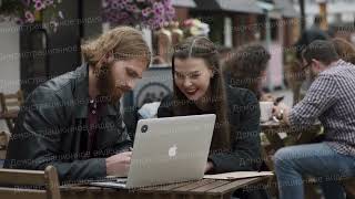 Парень и девушка за ноутбуком Apple в уличном кафе | Рекламный ролик заказать