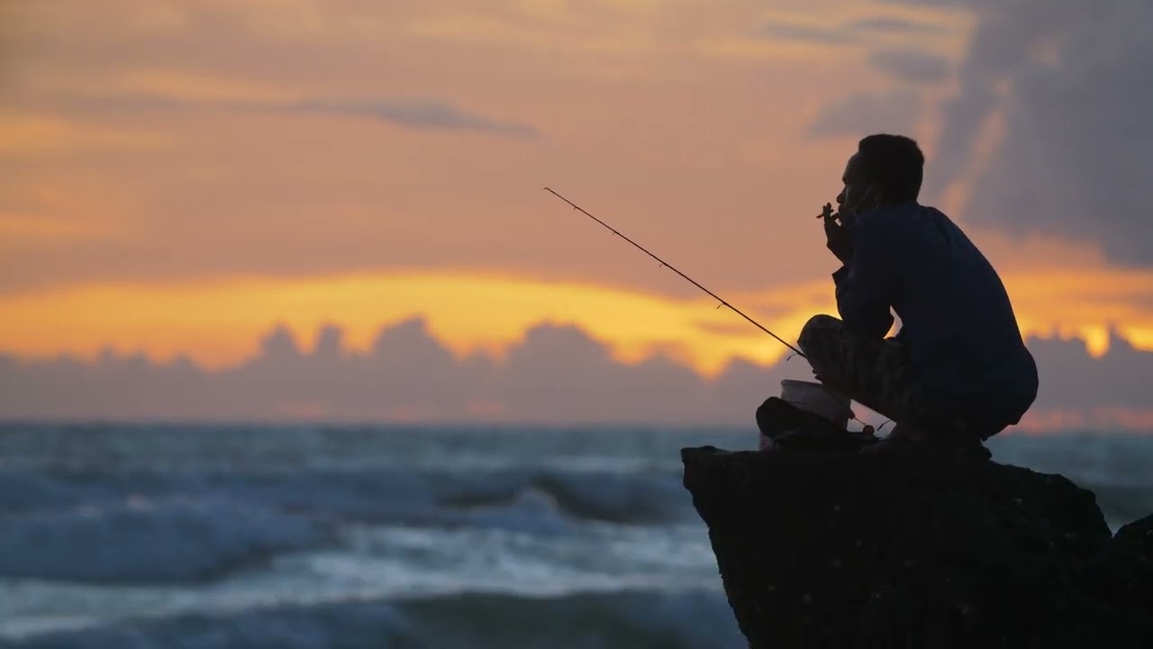 Handheld Long Shot of Fisherman Silhouetted Against Sunset - No Copyright Video