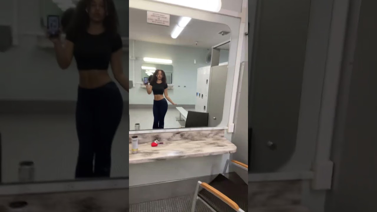 Curly Haired Woman in Gym Locker Room Taking a Mirror Selfie