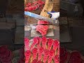 Slicing fresh red ginger with a manual industrial cutter for traditional medicine preparation