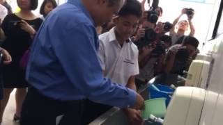 Minister Masagos helping student wash hands from a ladle in the canteen of Woodgrove Secondary screenshot 3