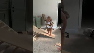 Little boy walks up wooden slide in house then falls forward and faceplants
