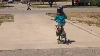 Boy flips over handlebars of tricycle in background