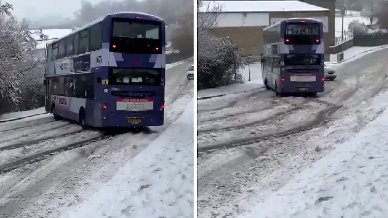 Double decker bus skids in the snow right at another car 