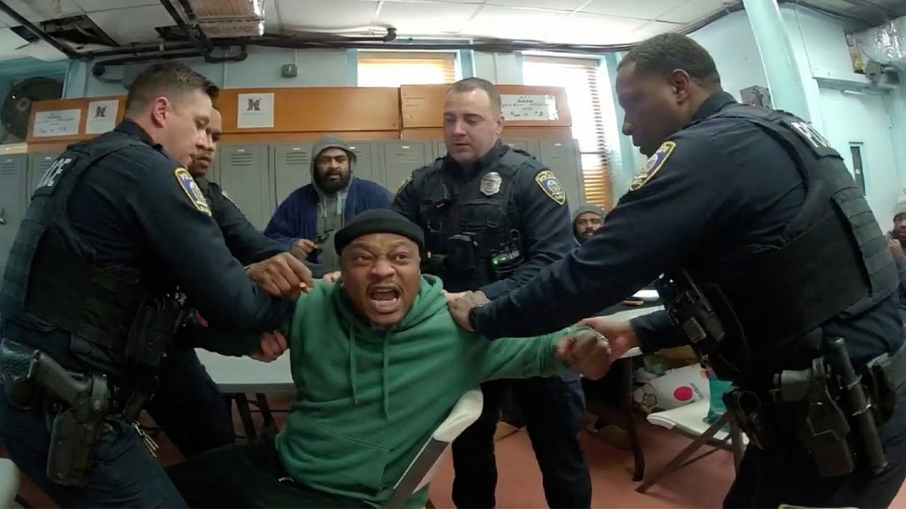 Подозреваемый спорит о личности, а затем пинает полицейскую машину.