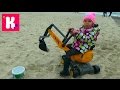 Катя играет на пляже в песке с экскаватором