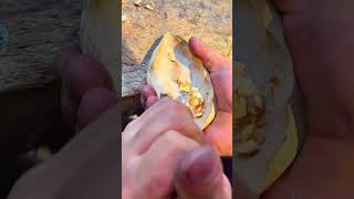 carving a piece of wooden block with a sharp chisel tool to create a hollow curved craft object