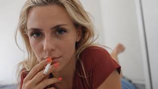 blond woman smoking on bed