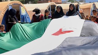 نساء في أحد مخيمات ريف عفرين يخطن علم الثورة بطول 25 متر