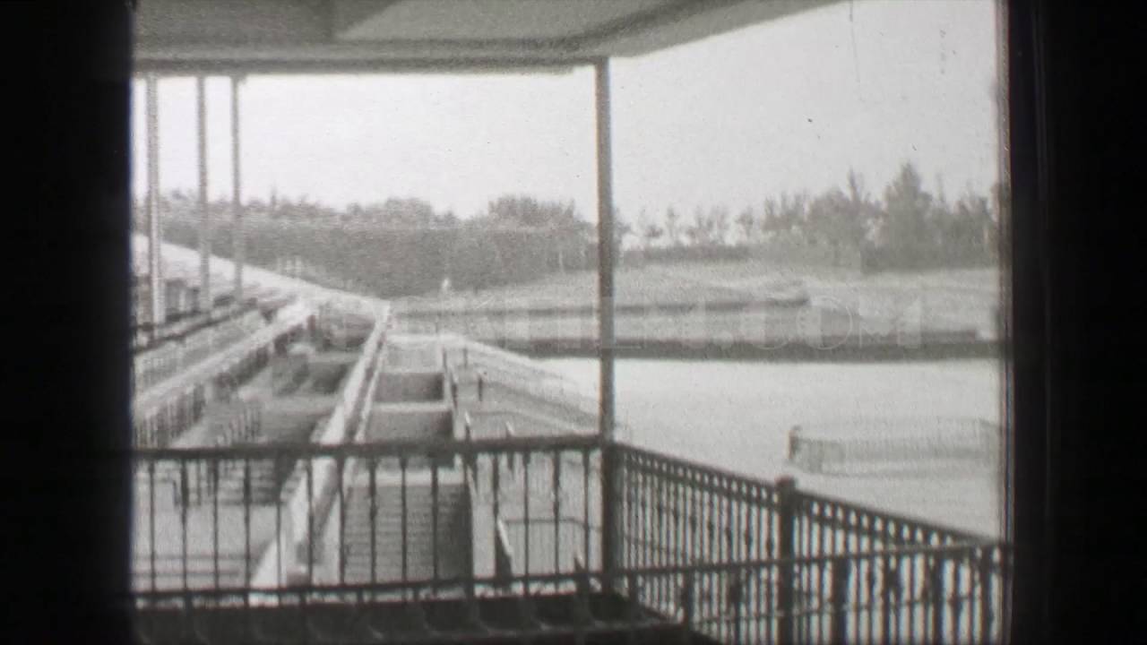 1938: Hialeah Park horse racetrack men tour empty epic stadium structure. HIALEAH, FLORIDA