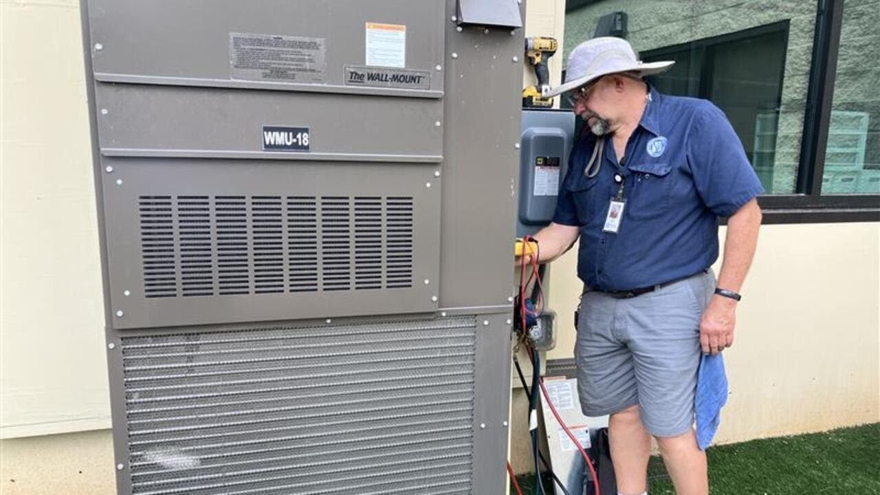 School maintenance workers check A/C units in heat