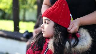 Adult hands putting a warm red winter hat on a young Armenian girl's head