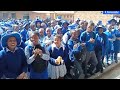 Njube High School students sing soon after their girls' rugby team.