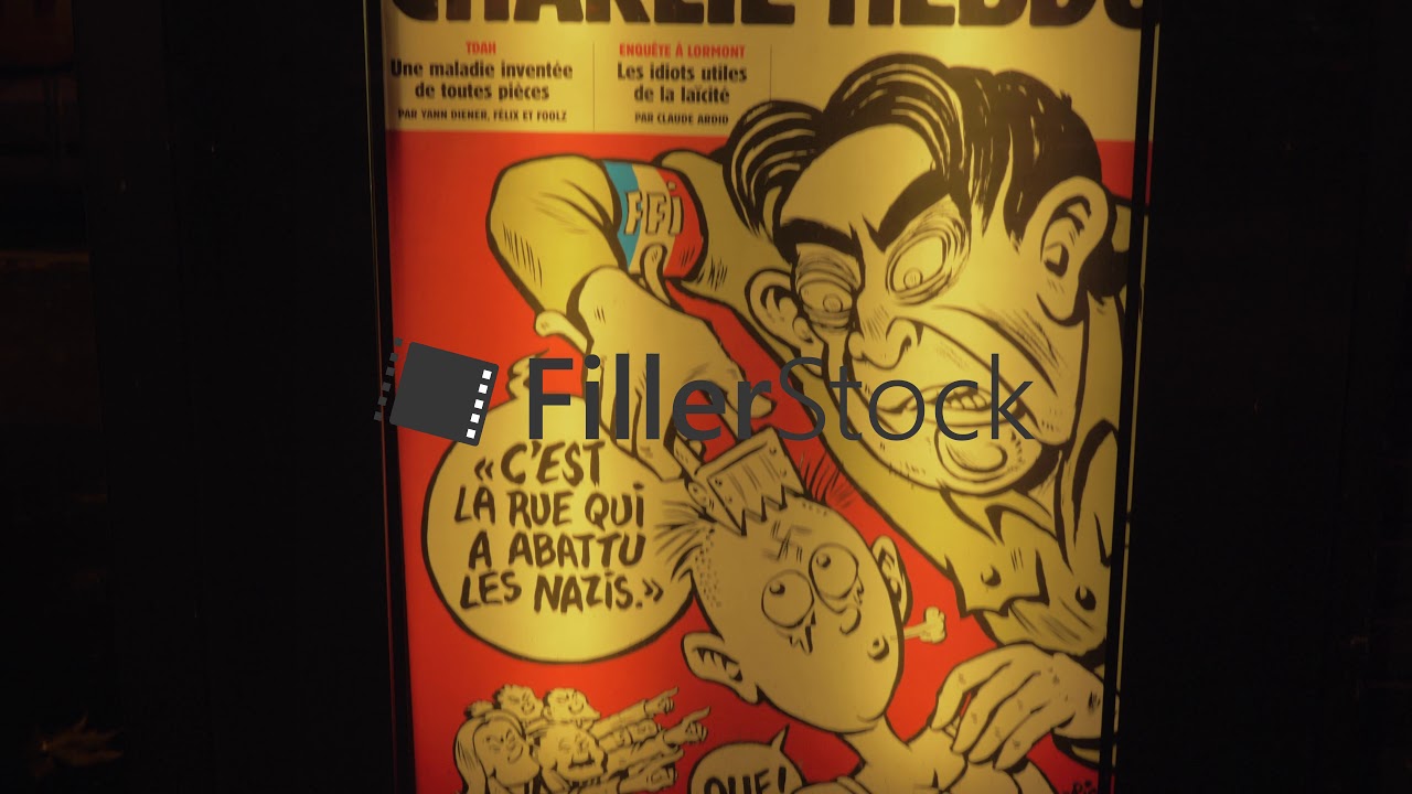 Poster of satirical magazine Charlie Hebdo in the street at night. Paris, France