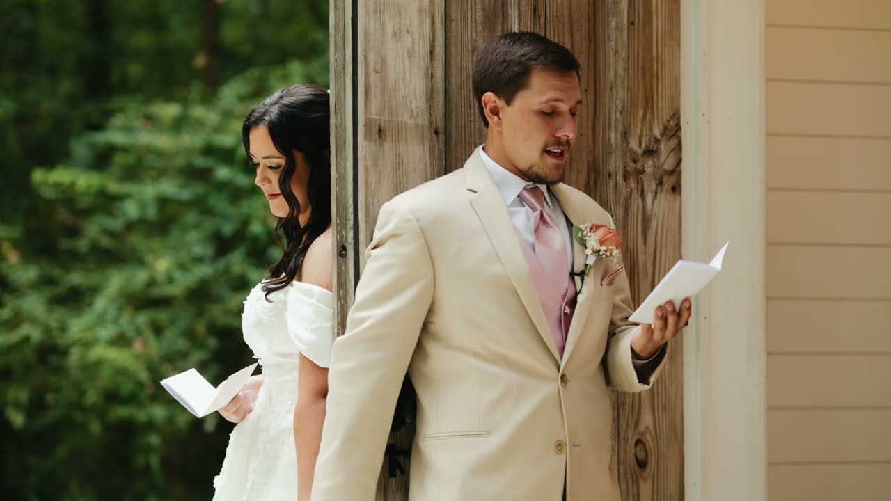 Groom reading a letter by a wooden door while his bride waits on the other side at Bird Song Chapel in Goldsboro, NC