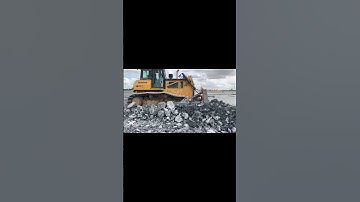 The Heavy Machine Bulldozer Pushing Rock For Backfill Uploading Dump Truck On Construction.