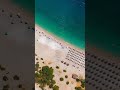 Vertical video. Oludeniz, Turkey. Aerial drone view of vibrant Oludeniz Beach with rows of colorf...