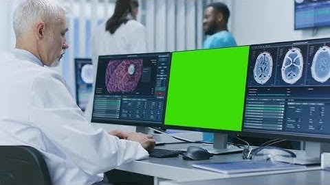 Scientist Working with Mock-up Green Screen and CT Brain Scan Images on a Personal Computer in