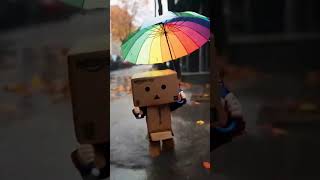 Danbos Rainy Day Adventure Cute Cardboard Robot With A Rainbow Umbrella