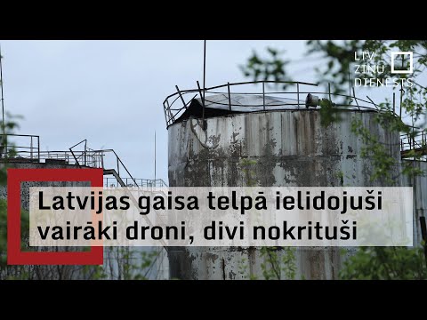 Storage tanks at the Rēzekne oil-storage site under a Latvian Television caption reporting several drones entering from Russia, two of them crashing.