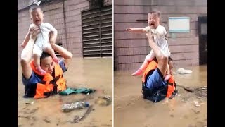 Incredible moment hero cop wades chest-deep through water carrying baby aloft