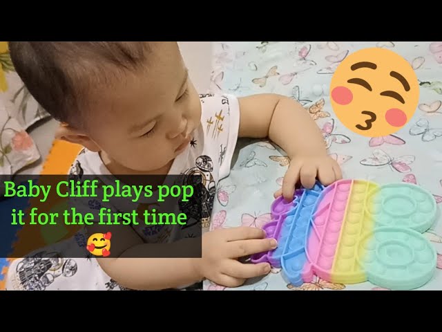 One year old baby plays pop it class=