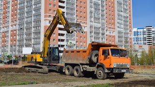 Экскаватор LOVOL FR245E2 и самосвалы КамАЗы-55111. Работа по погрузке плодородного слоя земли.