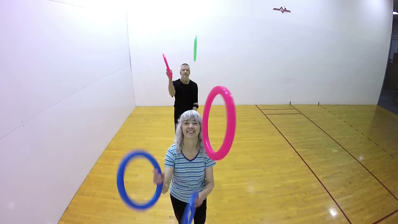 Woman Performs Pass Juggling Trick With Man While Looking Away From Him - 1217888-7