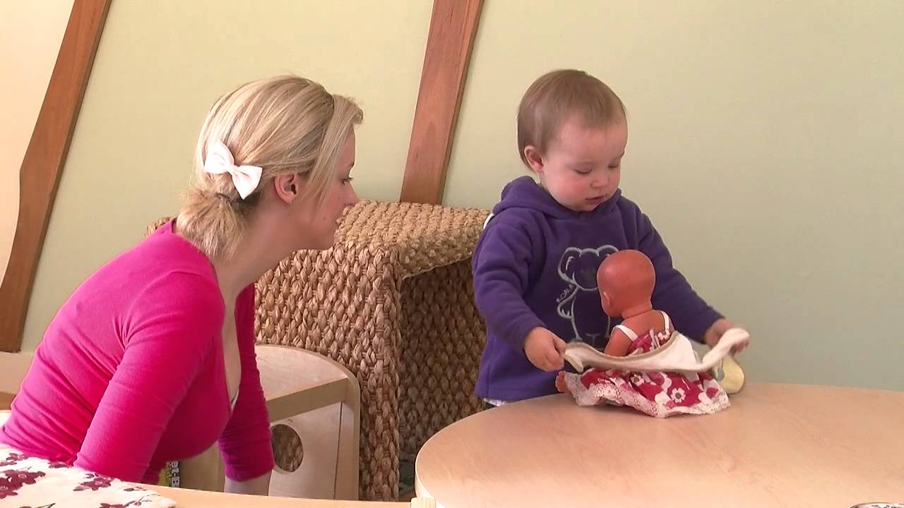 Connecting with Practice NQS PLP - A very young child putting a bib on a doll