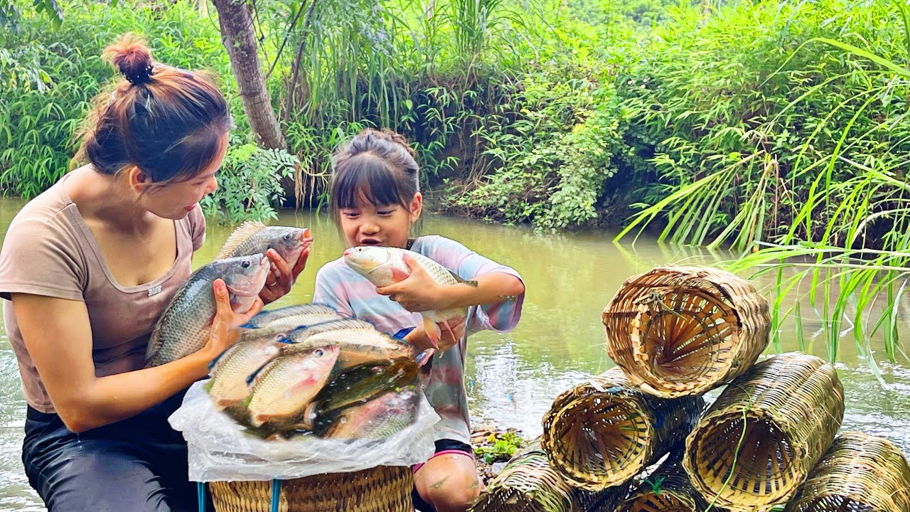 Single mother and daughter set fish traps in the stream during flood ...