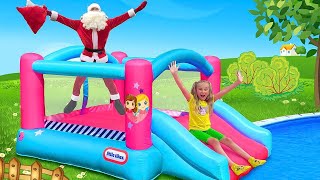 Sasha y Santa descienden de los toboganes de agua y juegan juegos activos con juguetes inflables