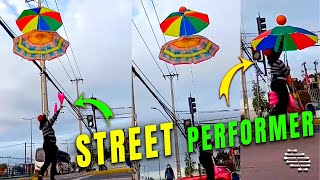 Street Performer Balance Two Vertical Umbrellas While Juggling Clubs
