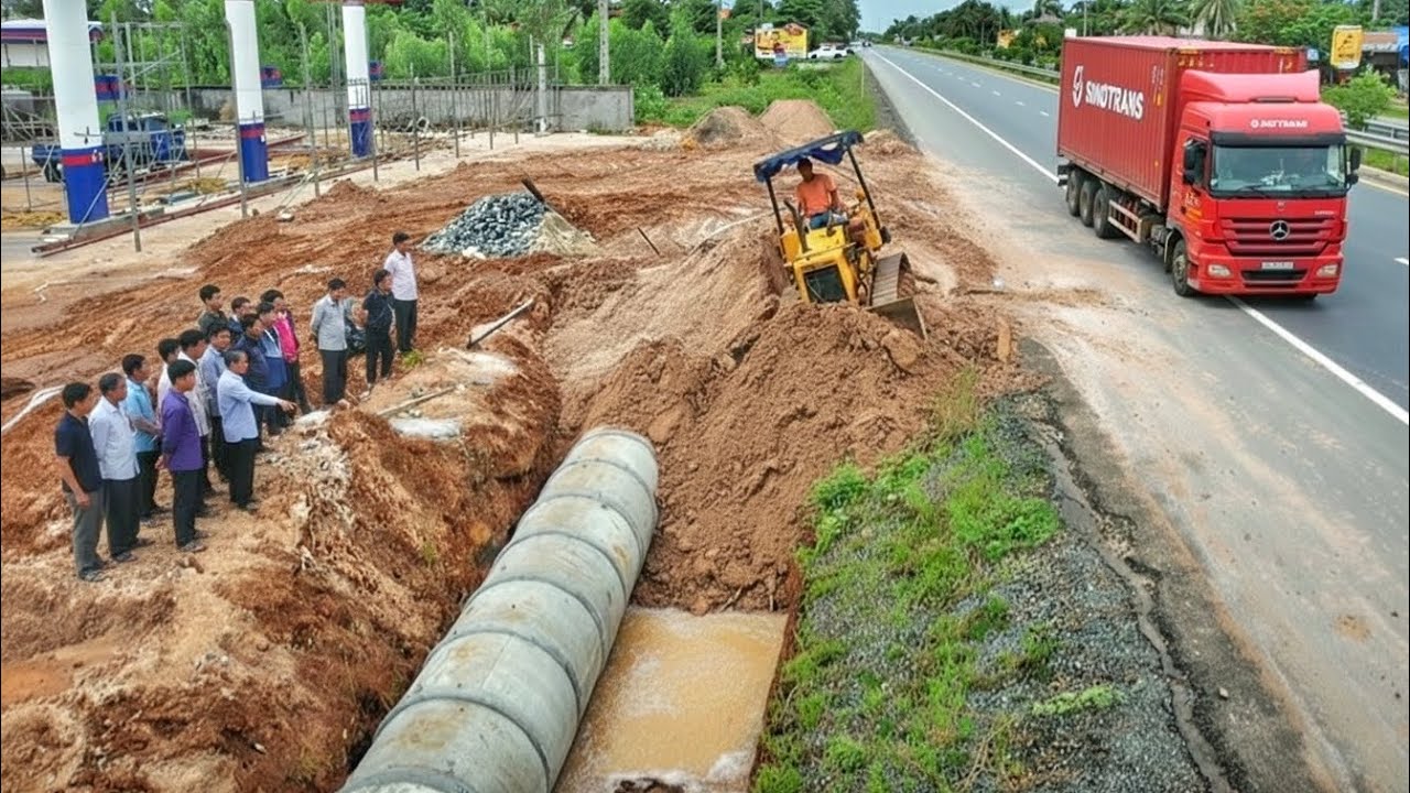 Clearing soil to bury the drainage system next to the road. Drivers passing by must be very careful.