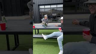 Little boy dances to music while standing on picnic table then falls back and lands on AstroTurf