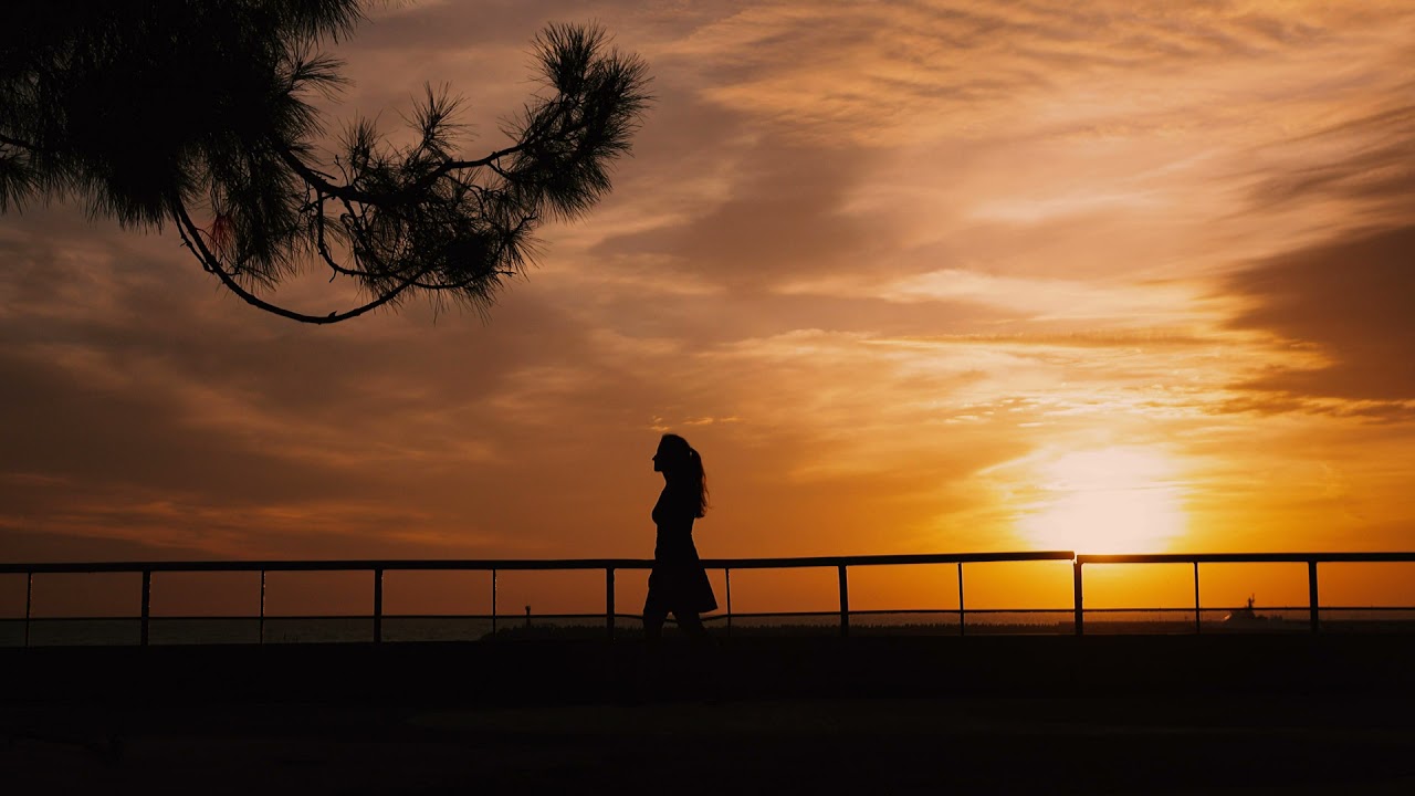 Femme rétro éclairée marchant au coucher du soleil