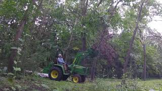 John Deere 3038e pulling dead branches from the trees
