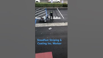 Steadfast Striping & Coating Inc. Worker lettering parking spaces