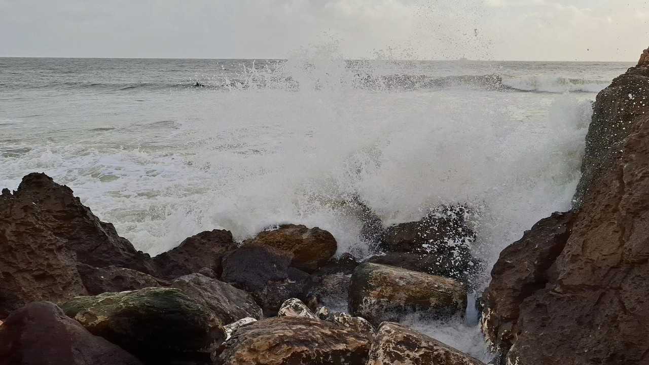 Ocean Waves shape the rocks. Surfers enjoy the power of nature. The ...